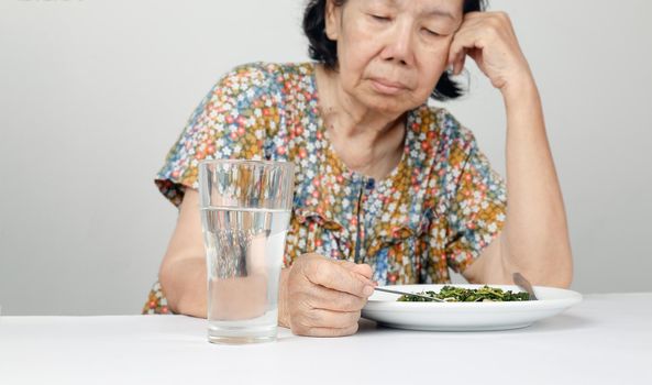 Elderly asian woman bored with food