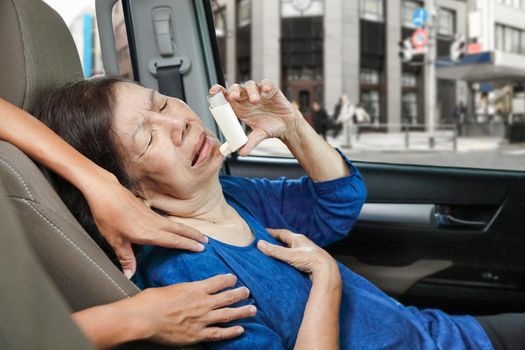 Elderly woman choking and holding an asthma spray inside car on the way