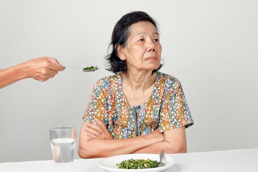 Elderly asian woman bored with food