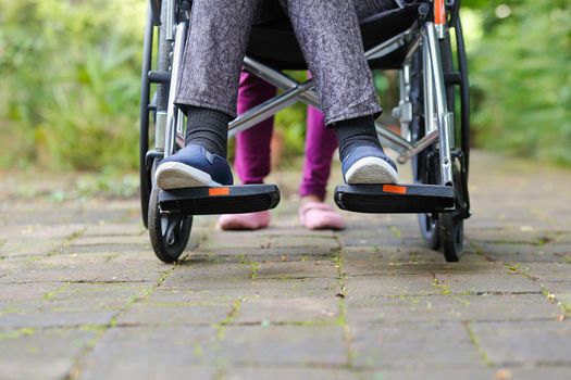 elderly woman in wheelchair walking with caregiver