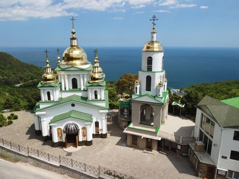 Christian church on a background of mountains. Temple of the Holy Archangel Michael in Oreanda. The southern coast of Crimea. Located on a rocky cliff and is surrounded by beautiful vegetation