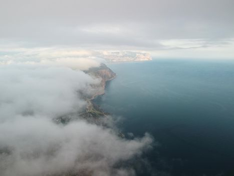 Footage B roll Aerial view drone flying above white clouds dense fog move quickly. Drone flies high back in blue sky through fluffy clouds. Beautiful foggy and cloudy slow moving Aerial view. Fog sea.