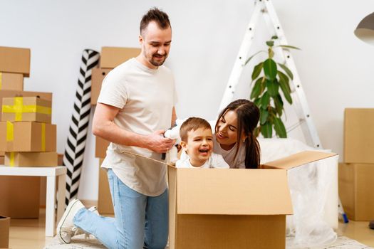 Parents and son packing boxes and moving into a new home having fun