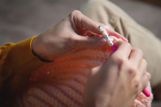 female hands close-up, crocheting clothes on the sofa at home, handmade.