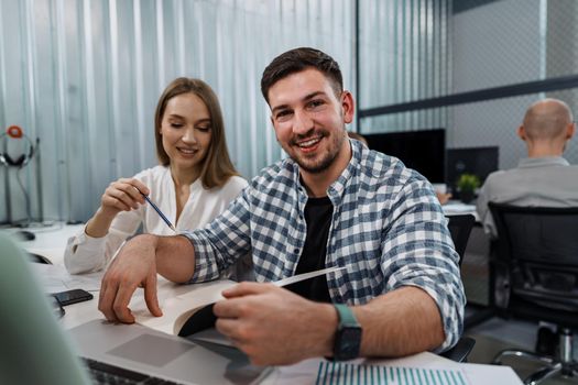 Two entrepreneurs man and woman sitting together working in an office, close up