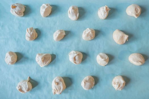 Homemade french milk-colored meringues on bluet paper. flatley composition: delicious homemade meringues on craft paper