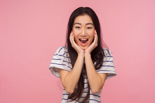 Wow, unbelievable success, Portrait of amazed girl with long hair in striped t-shirt screaming in surprise, looking shocked and rejoicing in victory. indoor studio shot isolated on pink background