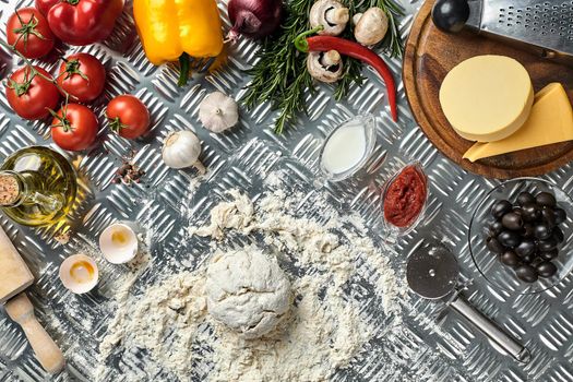 Ingredients and dough for making pizzas with an overhead view on freshly mixed mounds of pastry, a jar of olive oil and pot of tomato sauce, overhead view on metal background. Top view. Flat lay. Still life