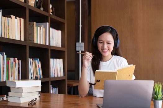 Happy asian woman sit at desk at home write study online on computer. Smiling young mixed race female work distant on laptop, take course on web. Education, learning concept