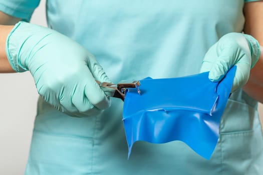Dentist's hands in latex gloves with a dental hole punch, a rubber dam and a metal frame. Medical tools concept.
