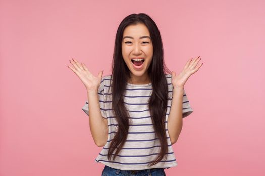 Wow, I won, Portrait of surprised happy girl with long hair in striped t-shirt screaming in amazement, looking shocked and rejoicing unexpected victory. indoor studio shot isolated on pink background