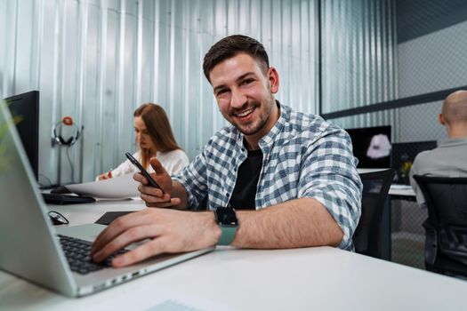 Portrait of young man sitting and working at his desk in the office, close up