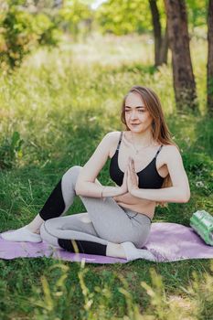 Yoga woman on green grass girl relaxes in the field. Yoga woman in green park girl doing gymnastics outdoors. Meditating woman in meditation in yoga pose practices outdoors