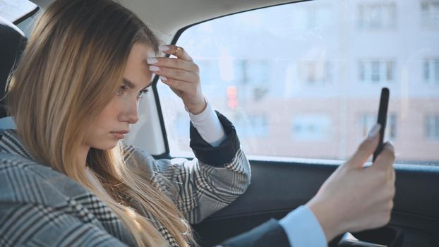 The girl in the car is looking at her phone like it's a mirror