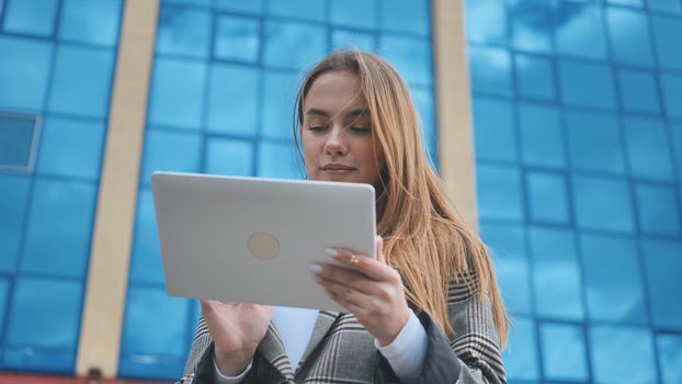 A young girl student works with a white tablet in the city