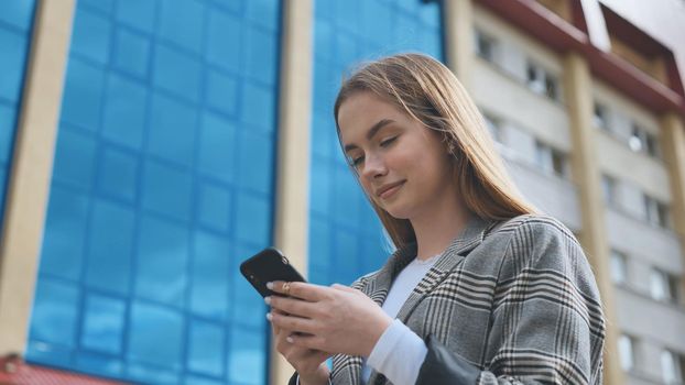 A girl walks through town and looks at her smartphone