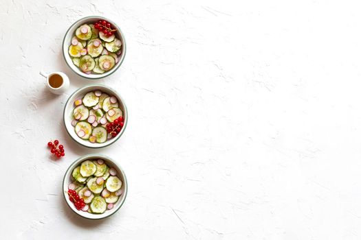 radish and cucumber salad served in a three small round bowls in a row, top view, copy space