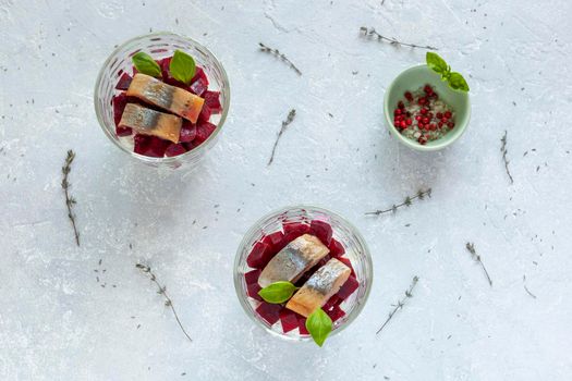 smoked hering and beet cold salad served in a glasses. top view