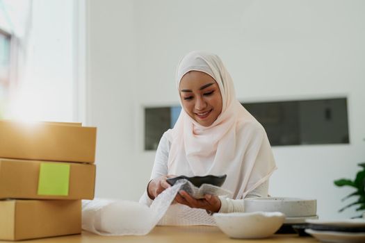 Asian muslim owner packing products preparing toshopping and make arrangements for delivery online while he works at home