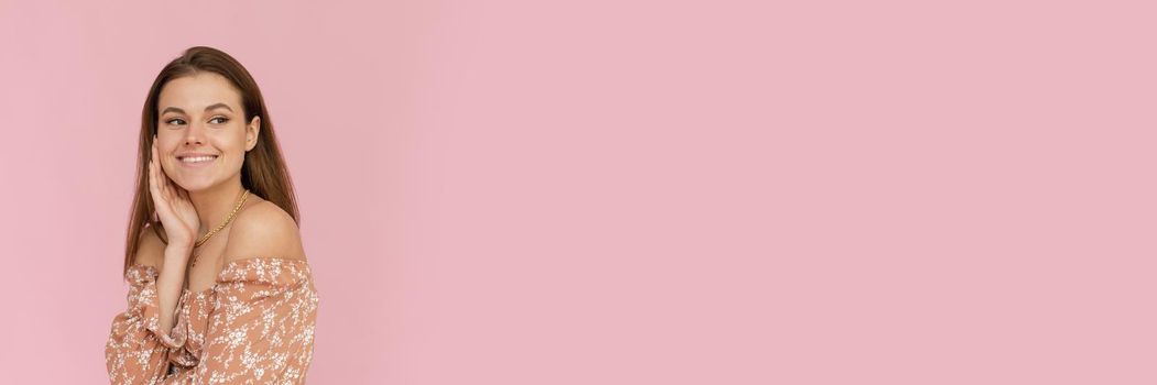 Pretty young woman in a beige dress on a pink background with copy space. Summer concept. Web banner.