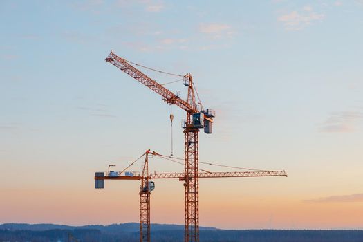 building cranes on the construction site at sunset background
