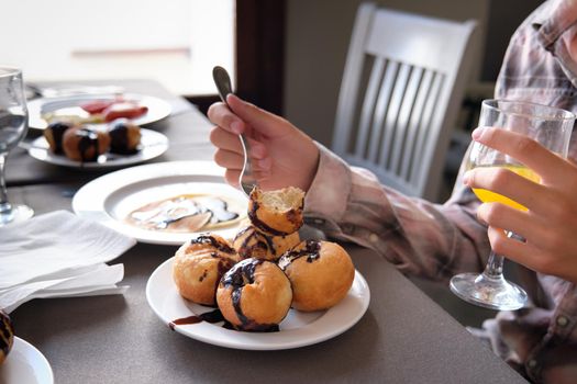 Donuts lying on a plate doused with chocolate during a young man's breakfast.