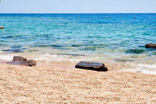 Sandy beach with rocks on the shore and water.