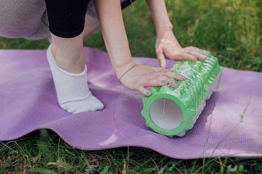 Woman practicing yoga and meditating outdoors. Girl preparing material for practice class in garden. Female happiness and yoga concept. During the quarantine due to the spread of the coronavirus