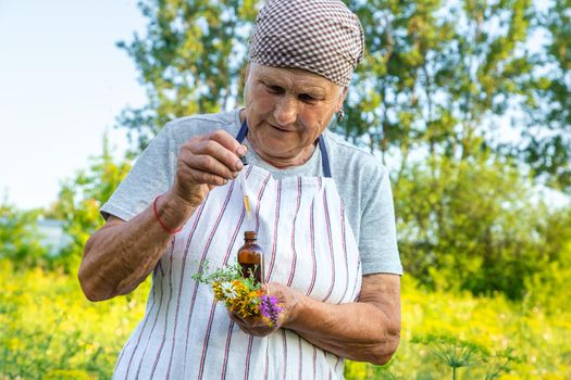 Old woman makes herbal tincture. Selective focus. Nature.