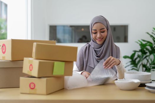Asian muslim owner packing products preparing toshopping and make arrangements for delivery online while he works at home