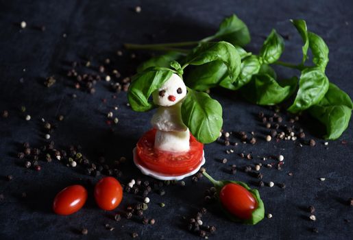 creative snowman canapes of mozzarella and tomatoes on a background of red poinsettia and a scattering of black pepper and green basil. High quality photo