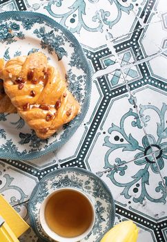 flat lay food, sweet puff, tea in a vintage porcelain cup and stack of books, strange angle, bouquet of yellow fading tulips in a vase,. High quality photo