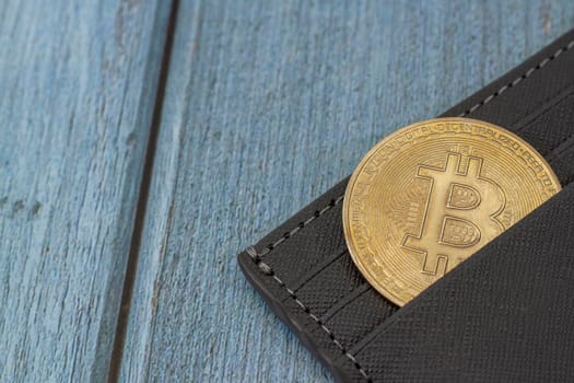 bitcoin gold coin place in wallet on blue wooden background. Online payment technology, digital wallet, computer financial, digital blockchain, bitcoin stock, cryptocurrency trading and mining investment concept.
