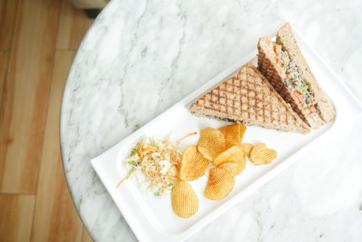 Tuna sandwich and chips on a plate on table