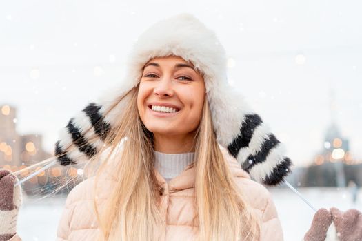 Medium shoot portrait of romantic european lady wears stylish winter jacket and funny fluffy hat in snowy day. Outdoor photo of inspired blonde woman enjoying free time in winter city. Christmas