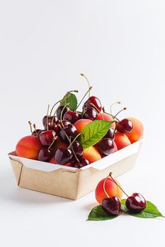 Apricots and cherries in paper packaging on a white background. the concept of eco-friendly packaging without plastic. copy space