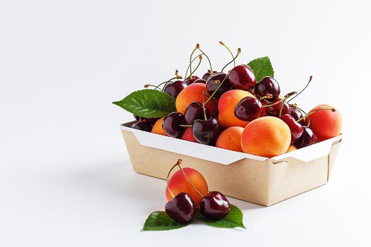 Apricots and cherries in paper packaging on a white background. the concept of eco-friendly packaging without plastic. copy space