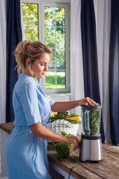 Blond happy woman turning on blender to make smoothie, healthy breakfast in summer morning, cooking raw vegetables, preparing green salad, low calorie diet, vegetarian nutrition, organic detox meal