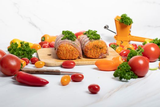 minced meat sausages in bacon with green parsley and fresh vegetables, cherry tomatoes, bell peppers, colorful food . High quality photo