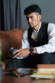 Portrait of Asian Businessman with cup of coffee and sitting at cozy sofa
