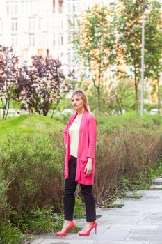 Full length portrait of serious beautiful young successful businesswoman in elegance style standing on green park, posing with confident face and looking at camera. Outdoor