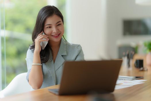 Image of Happy Asian Business woman discussing with her business partner by cell phone. Finance and brainstorm concept