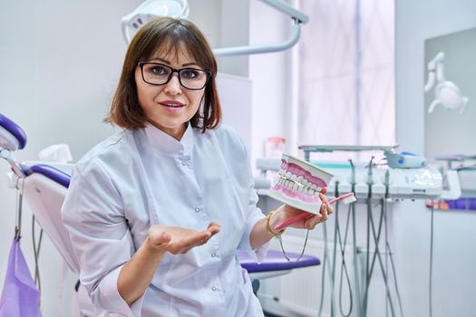 Doctor dentist consulting online looking at webcam showing dental jaw with teeth. Doctor making video call chat conference, in dental office. Medicine, telemedicine, technology, health care concept