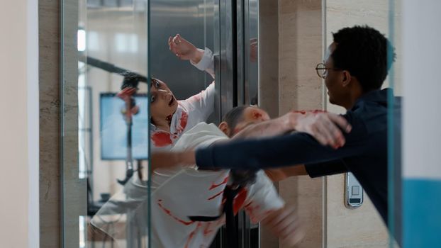 Agency employee going home when creepy looking monsters coming out of elevator. Adult worker leaving work when apocalyptic spooky zombies chasing him downstairs inside building.