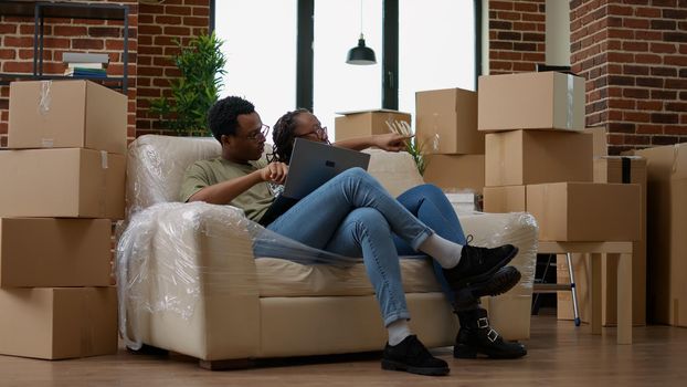 Married couple buying furniture online on laptop to decorate new house, moving in together. Doing online shopping for interior decoration after relocation, rented apartment flat.