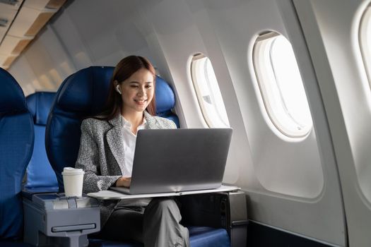 Close up hand of business asian woman uses laptop while flying on airplane near window