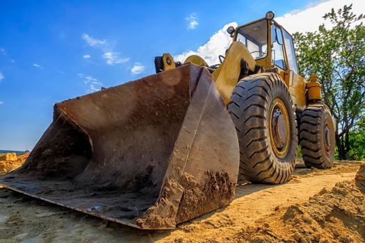 day view of a yellow excavator with a shovel at a construction site
