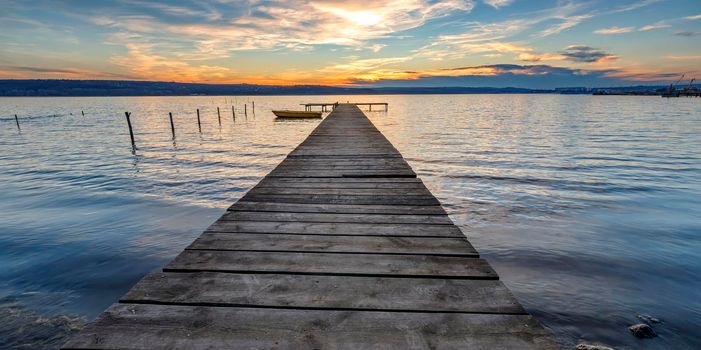 Scenic view of exciting twilight at the shore with a wooden pier and moored boat