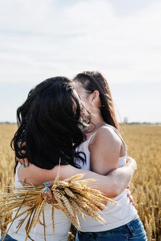 Freedom, friendship concept. Two smiling female friends in white shirts in the wheat field