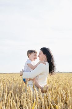 Happy family on a summer walk, mother and child walk in the wheat field and enjoy the beautiful nature, at sunset